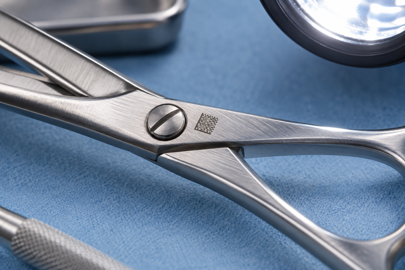 Close-up of a laser-marked identification square beside the hinge of a stainless surgical instrument